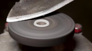 Küçük elektrikli bir tekerlekte eski metal bir bıçağı bilemek.