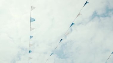 Mavi gökyüzüne ve beyaz bulutlara karşı beyaz ve mavi üçgen bayraklar