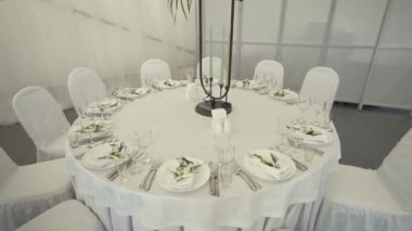 Okyanusta büyük bir çadırda, üzerinde beyaz masa örtüleri olan büyük yuvarlak sunucu masalarında.