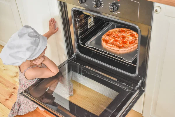 girl child cooks pizza in the oven photo without filter