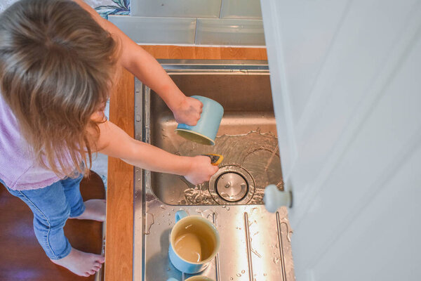 a child washes mugs in the sink photo without a filter