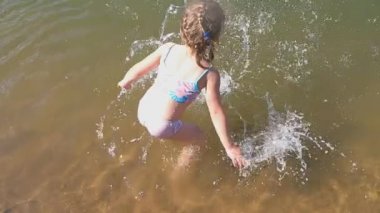 Güneşli bir günde kumsalda denize düşen küçük bir kız.