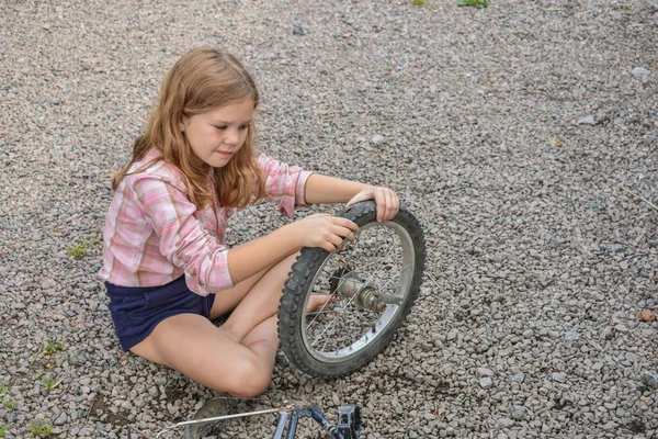 Bir kız çocuğu bisiklet tekerleğine zarar verdi ve işlemden geçmeden fotoğraf onarıyor.