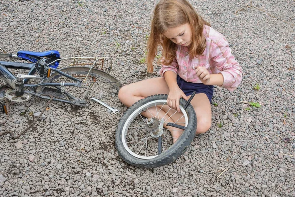 Bir kız çocuğu bisiklet tekerleğine zarar verdi ve işlemden geçmeden fotoğraf onarıyor.