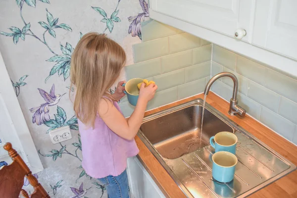 a child washes mugs in the sink photo without a filter