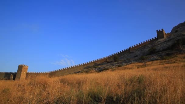 Нижній вигляд стародавньої генуезької фортеці в місті Судак. Історична пам'ятка архітектури на заході сонця. Крим. — стокове відео