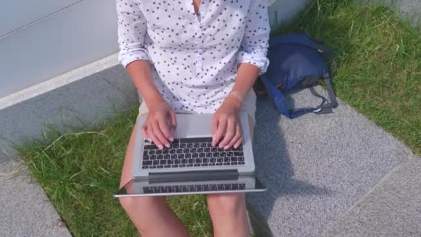 Ovanifrån på kvinna som arbetar med bärbar dator i stadsparken. Utomhus arbetsplats för frilansare på sommaren. — Stockvideo