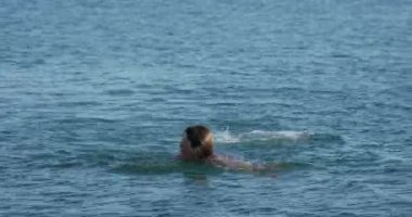 Adam denizde yüzüyor. Günbatımında okyanus dalgalarında yıkanan adam. Aktif açık hava eğlencesi. Yaz titreşimleri. Doğayla birlik.