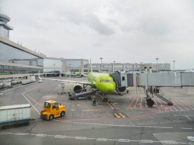 MOSCOW, Rusya - 28 Haziran 2021. Yolcular jet köprüsü boyunca S7 Havayolları tarafından yeşil uçağa biniyorlar. Domodedovo Havaalanı.