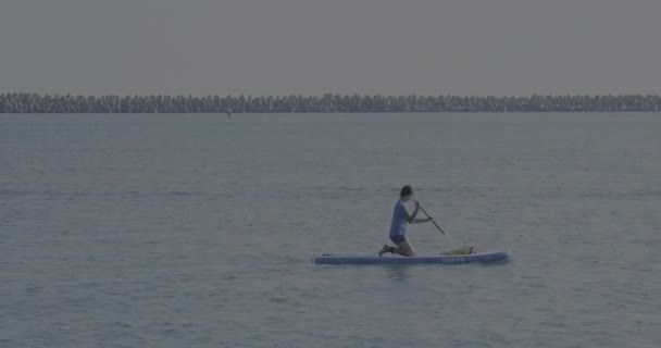 Handsome paddle boarder. Sportsman on knees paddling on stand up paddleboard. SUP surfing. Active lifestyle. Outdoor recreation. Vacation on seaside. — Stock Video