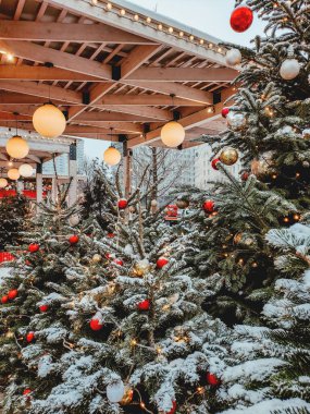Kırmızı ve altın taşaklı Noel ağacı. Şehir sokaklarında yeni yıl kutlaması için ampullü açık hava dekorasyonları..