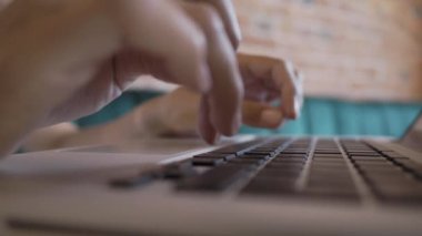 Kadın, kırmızı tuğlalı duvarları olan bir kafede çalışıyor. Laptop klavyesinde kadın tipler. Çatı katı iç mimarisi ile ortak çalışma merkezi. Serbest iş yeri.