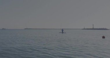 Yakışıklı kürekçi seni. Sporcu dizlerinin üzerinde ayakta kürek çekiyor. Sup sörfü. Aktif yaşam tarzı. Açık hava eğlencesi. Deniz kenarında tatil..