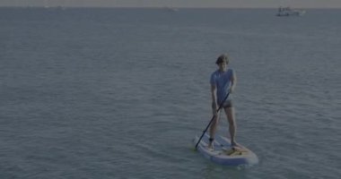 Yakışıklı kürekçi seni. Kürek çeken sporcu ayağa kalkıyor. Sup sörfü. Aktif yaşam tarzı. Açık hava eğlencesi. Deniz kenarında tatil..