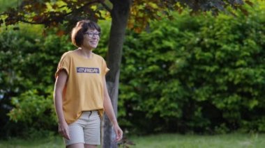 Kadın çimlerde frizbi oynuyor. Yaz titreşimleri. Açık hava eğlence aktivitesi. Aile hayatı. Arka bahçede spor maçı.