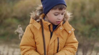 Sahadaki kuru otlu çocuk. Sonbahar sezonunda çocuklar için açık hava aktivitesi. Çocuklar sonbahar günleri için moda..