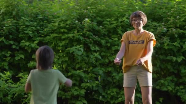 Madre e hijo juegan al frisbee en el césped. Vibras de verano. Actividad de ocio al aire libre. Vida familiar. Juego de deportes en el patio trasero. — Vídeo de stock