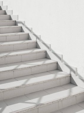 Korkuluklu, beyaz merdiven boşluğu. Taş basamaklarda güneş ışığı ve gölge. Kentsel geometri.