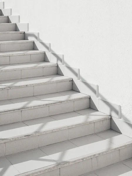 stock image White exterior of outdoor staircase with railing. Sunlight and shadow on stone steps. Urban geometry.