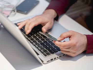 Adam online siparişi kredi kartıyla ödemek için dizüstü bilgisayar kullanıyor. İnternetten alışveriş ya da e-ticaret. Kablosuz teknolojilerin temassız ödemesi.