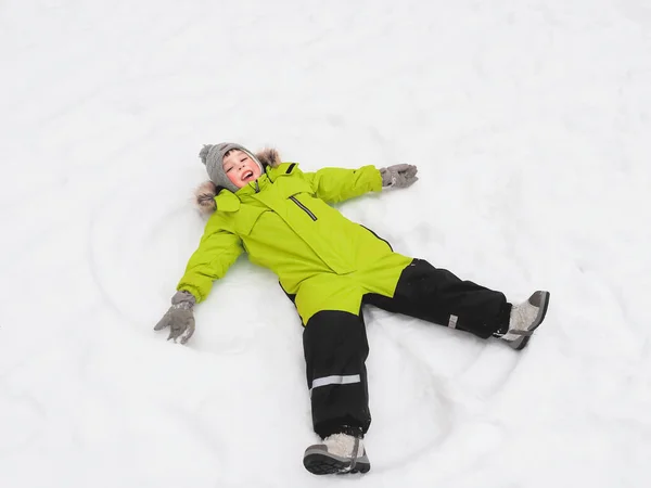 Lachen Jongen Groene Jumpsuit Het Maken Van Sneeuw Engel Vorm — Stockfoto