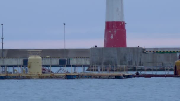 Mor gökyüzü arka planında kırmızı ve beyaz çizgileri olan eski deniz feneri. Günbatımında Sochi limanında navigasyon cihazı. Rusya. — Stok video