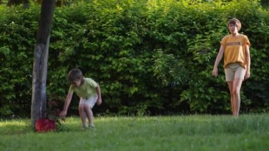 Anne ve oğlu çimlerin üzerinde frizbi oynuyorlar. Yaz titreşimleri. Açık hava eğlence aktivitesi. Aile hayatı. Arka bahçede spor maçı.
