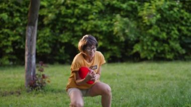 Anne ve oğlu çimlerin üzerinde frizbi oynuyorlar. Yaz titreşimleri. Açık hava eğlence aktivitesi. Aile hayatı. Arka bahçede spor maçı.