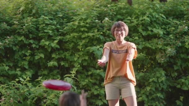 Moeder en zoon spelen frisbee op gras gazon. Zomer vibes. Vrijetijdsbesteding buitenshuis. Het gezinsleven. Sport spel in de achtertuin. — Stockvideo