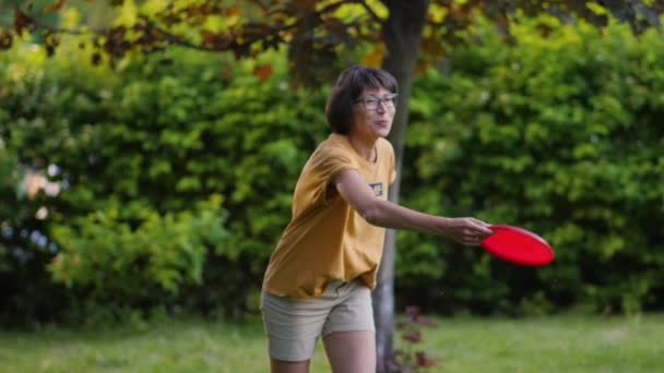여자들은 잔디 위에서 프리스비 놀이를 한다. 여름 풍경. 야외 레저 활동. 가정생활. 뒷마당에서 열리는 스포츠 경기. — 비디오