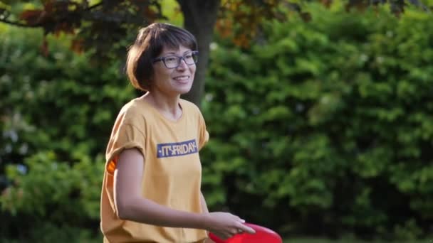 La mujer juega al frisbee en el césped. Vibras de verano. Actividad de ocio al aire libre. Vida familiar. Juego de deportes en el patio trasero. — Vídeo de stock