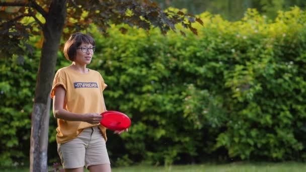 La mujer juega al frisbee en el césped. Vibras de verano. Actividad de ocio al aire libre. Vida familiar. Juego de deportes en el patio trasero. — Vídeo de stock