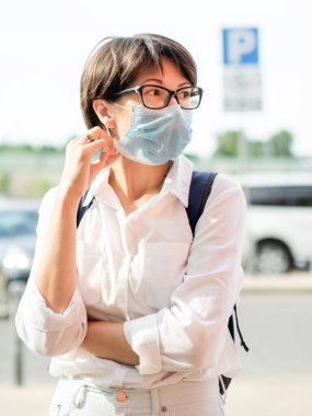 Kadın alışveriş merkezine girmeden önce yüzüne koruyucu maske takıyor. Coronavirus COVID 19 ihtiyati tedbir. Yeni normal.