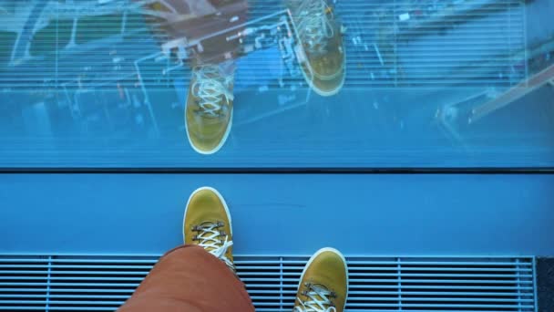 Draufsicht auf Männerfüße in gelben Lederturnschuhen. Der Mann steht in der Nähe eines Panoramafensters im Obergeschoss des Gebäudes. Urbane Mode der Millennials. — Stockvideo