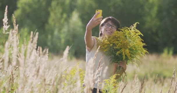 女性は、秋のフィールドで、一般的に黄金の棒と呼ばれるSolidagoを選んでいます。仕事中の花屋さん。黄色の花をインテリアの装飾花束として使用する. — ストック動画