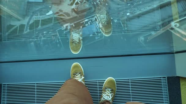 Draufsicht auf Männerfüße in gelben Lederturnschuhen. Der Mann steht in der Nähe eines Panoramafensters im Obergeschoss des Gebäudes. Urbane Mode der Millennials. — Stockvideo