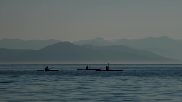 Silhouettes of tourists on kayaks moving on mountain range background. Summer recreation on Kamchatka peninsula, Russia. — Video Stock