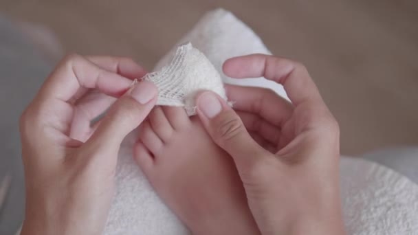 Matka si obvazuje dětský palec. Detailní záběr dětské nohy s obvázaným prstem. První pomoc v případě malých domácích zranění. — Stock video