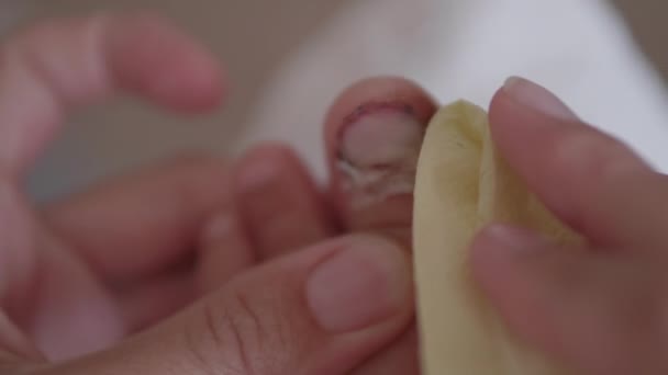 Mutter bindet ihren Kindern den großen Zeh. Nahaufnahme von Kinderfuß mit bandagiertem Finger. Erste Hilfe bei kleinen häuslichen Verletzungen. — Stockvideo