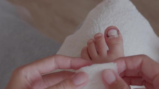 Mutter bindet ihren Kindern den großen Zeh. Nahaufnahme von Kinderfuß mit bandagiertem Finger. Erste Hilfe bei kleinen häuslichen Verletzungen. — Stockvideo