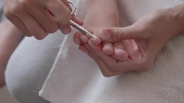 Matka si ostříhá nehty na dětských nohách. Detailní záběr dětské nohy. Procedura péče o pleť doma. — Stock video