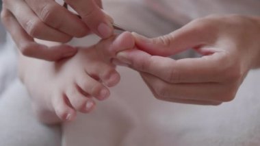 Anne, çocuklarının ayak parmaklarını kesiyor. Çocuk ayağının yakın plan fotoğrafı. Evde cilt bakımı prosedürü.