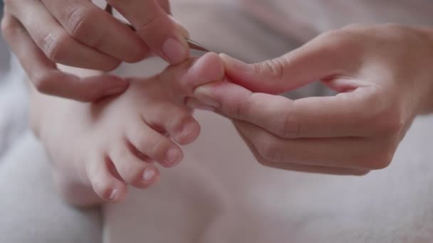 Matka si ostříhá nehty na dětských nohách. Detailní záběr dětské nohy. Procedura péče o pleť doma. — Stock video