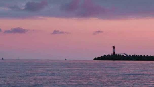 カラフルな夕日の背景に灯台のシルエット。ソチの港、ロシア. — ストック動画