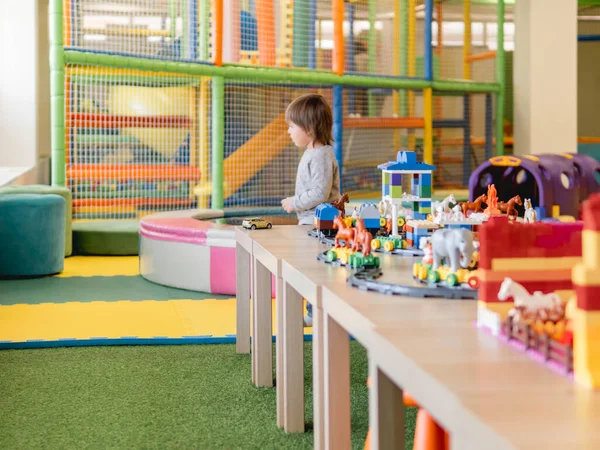 Toddler plays with colorful toy blocks. Little boy and toy constructor. Interior of kindergarten or nursery. Indoors leisure activity for children.