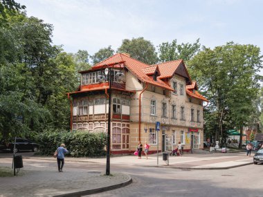 SVETLOGORSK, RUSSIA - 21 Temmuz 2019. Yerel halk, bakkal olarak kullanılan süs balkonlarıyla eski binanın önünden geçiyor..