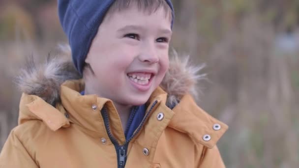 마른 풀을 가지고 들판에 있는 소년. 가을에는 아이들을 위한 옥외 레저 활동을 한다. 가을에 유행하는 아이들. — 비디오