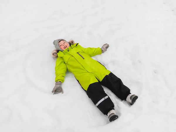 Lachen Jongen Groene Jumpsuit Het Maken Van Sneeuw Engel Vorm — Stockfoto