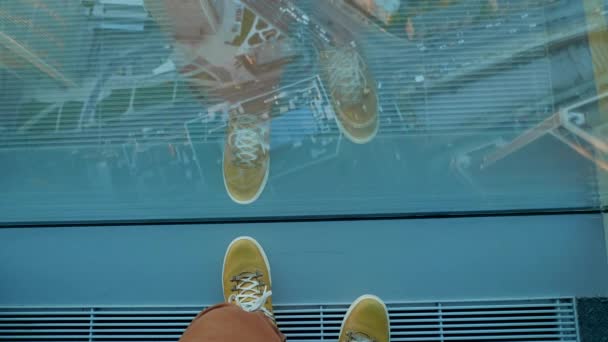 Vista dall'alto su piedi uomo in sneakers in pelle gialla. L'uomo si trova vicino alla finestra panoramica al piano superiore dell'edificio. Moda urbana di millennials. — Video Stock