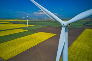 Aerial drone close up shot of wind mills rotating by the force of the wind and generating renewable energy.